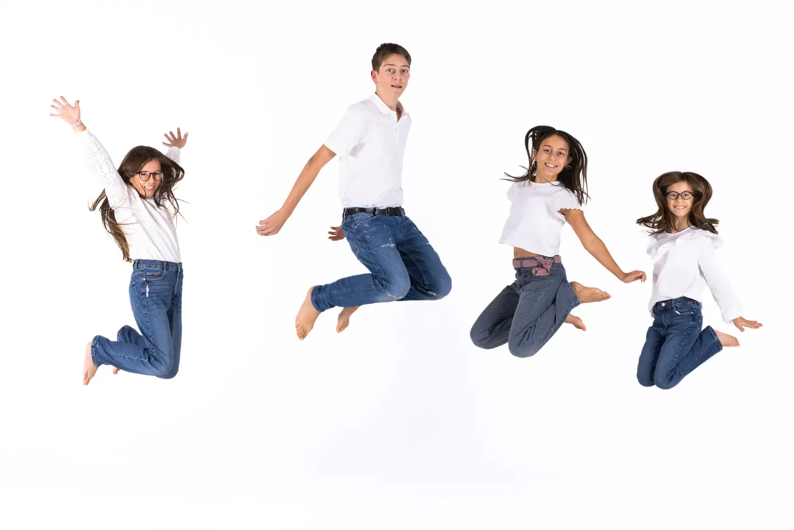Quatre enfants qui sautent en l’air sur fond blanc