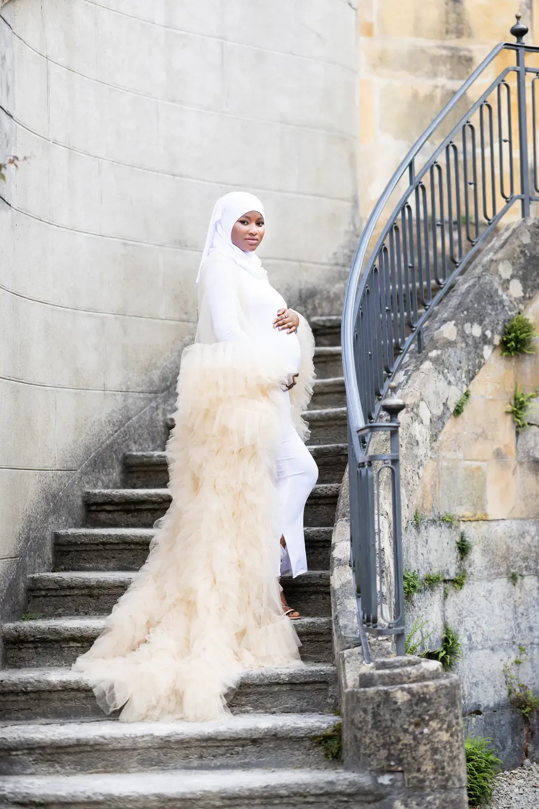 Future maman en robe de tulle sur un escalier de pierre ancien