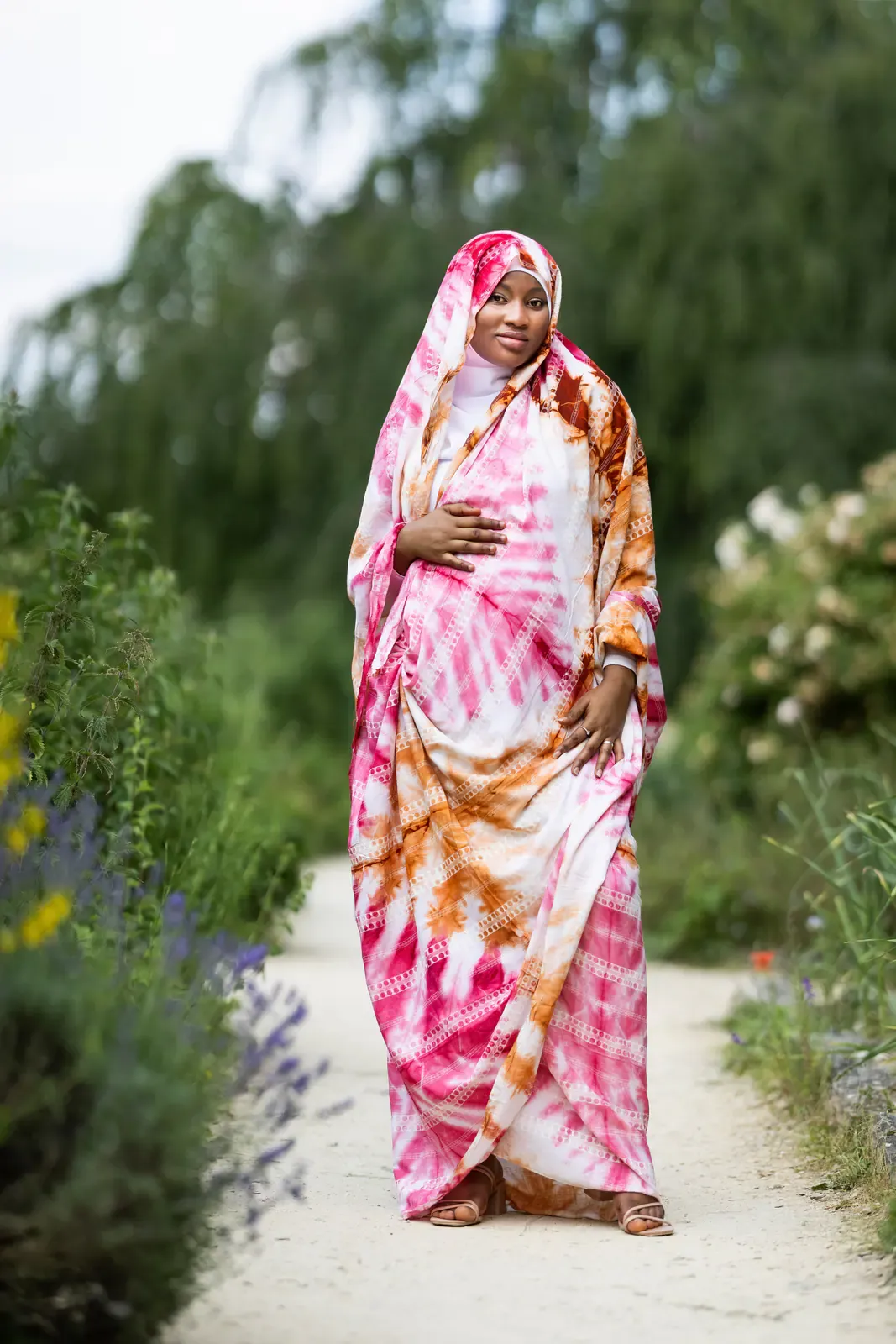 Future maman en robe fleurie dans un jardin