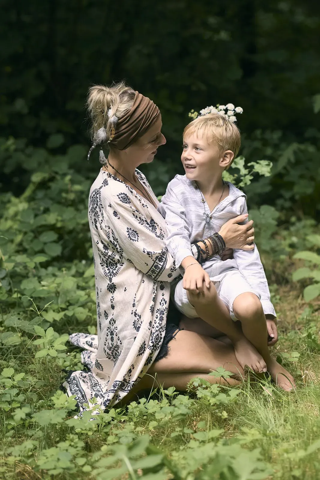 Mère et petit garçon couronné de fleurs, assis dans l'herbe