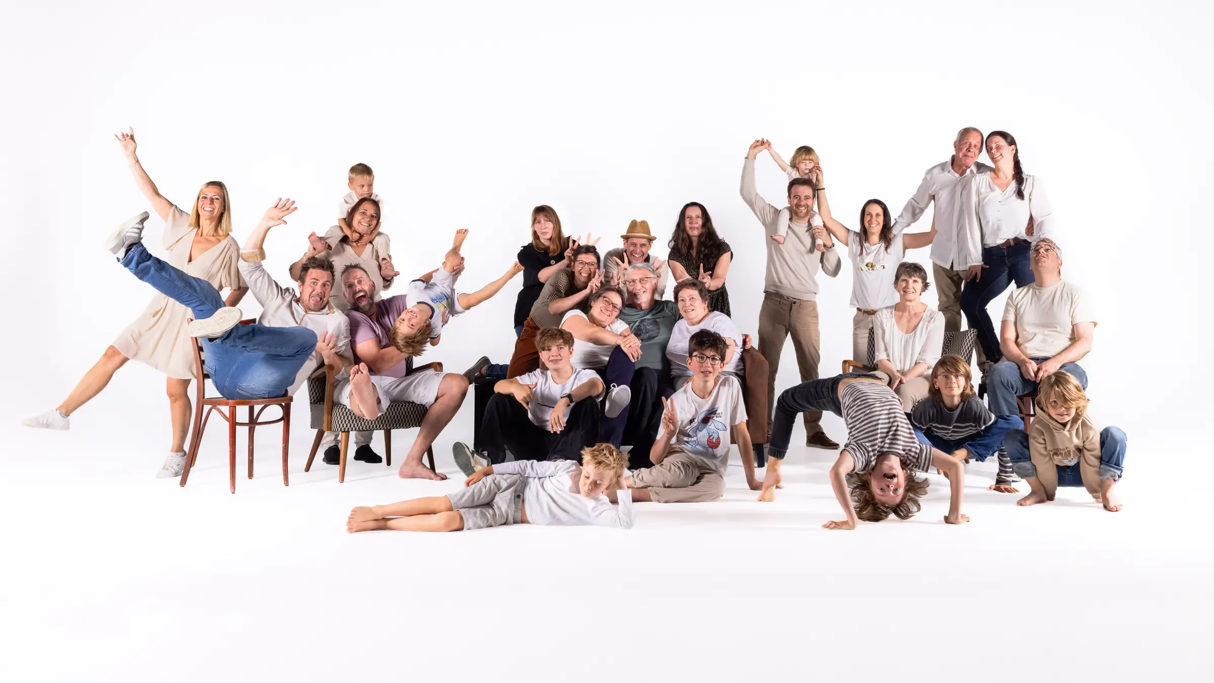 Grande famille en studio sur fond blanc, bras levés et éclats de rire